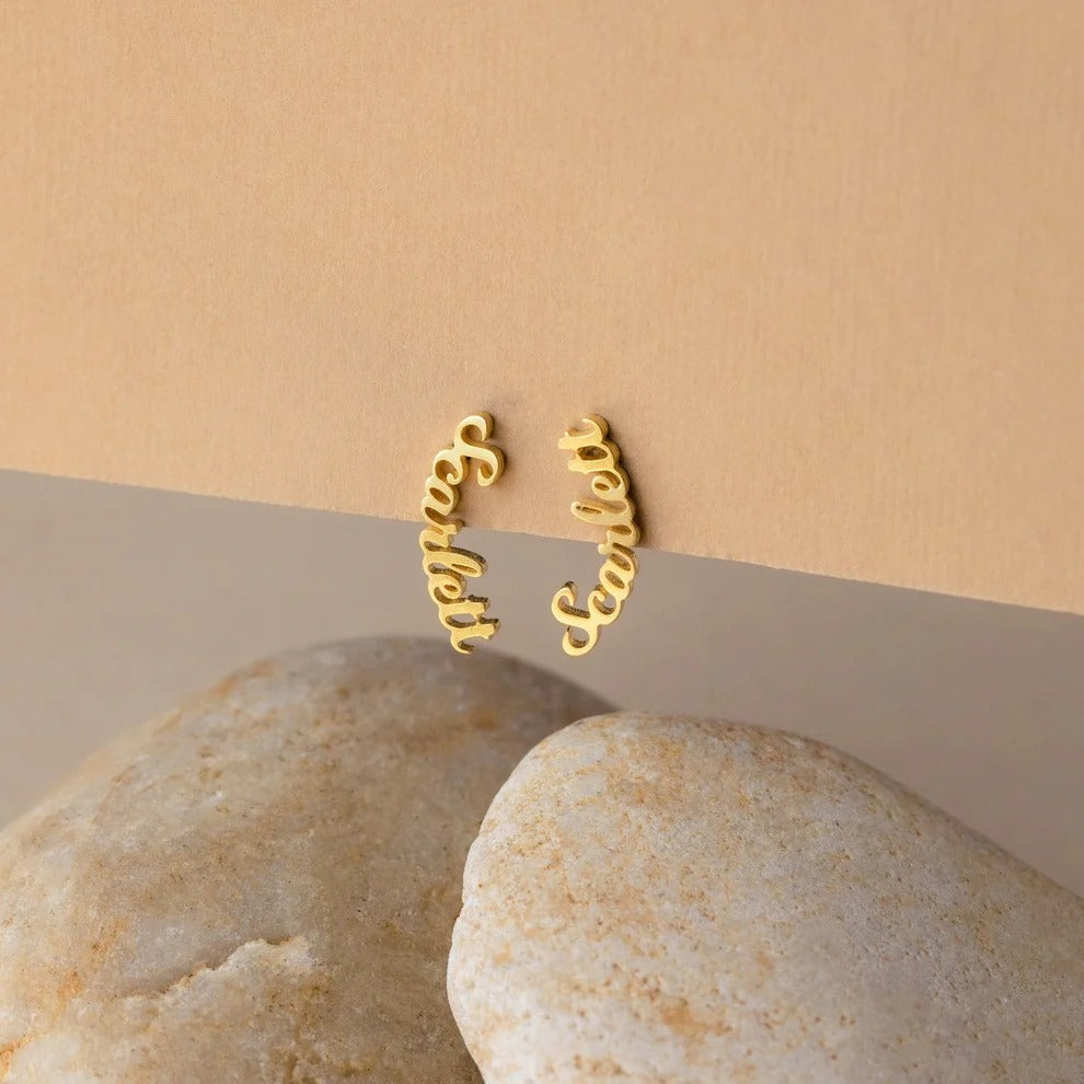 Gold hoop earrings on a beige stone surface