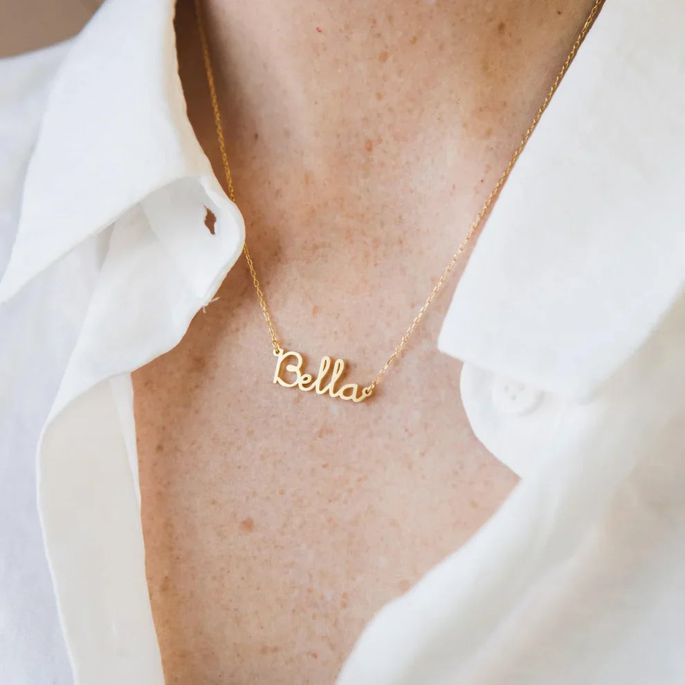 Gold 'Bella' necklace on a person wearing a white shirt