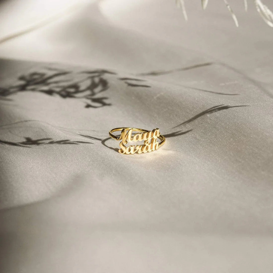 Gold ring with engraved text on a textured beige surface