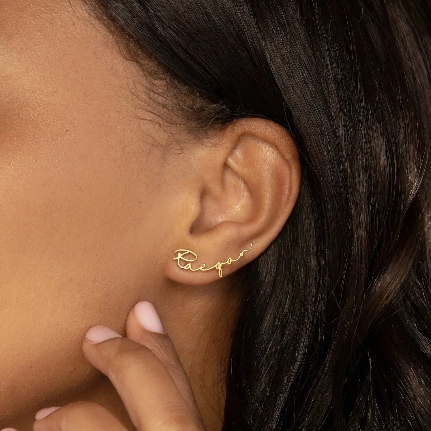 Gold ear cuff with 'Lifepan' engraving worn by a person.