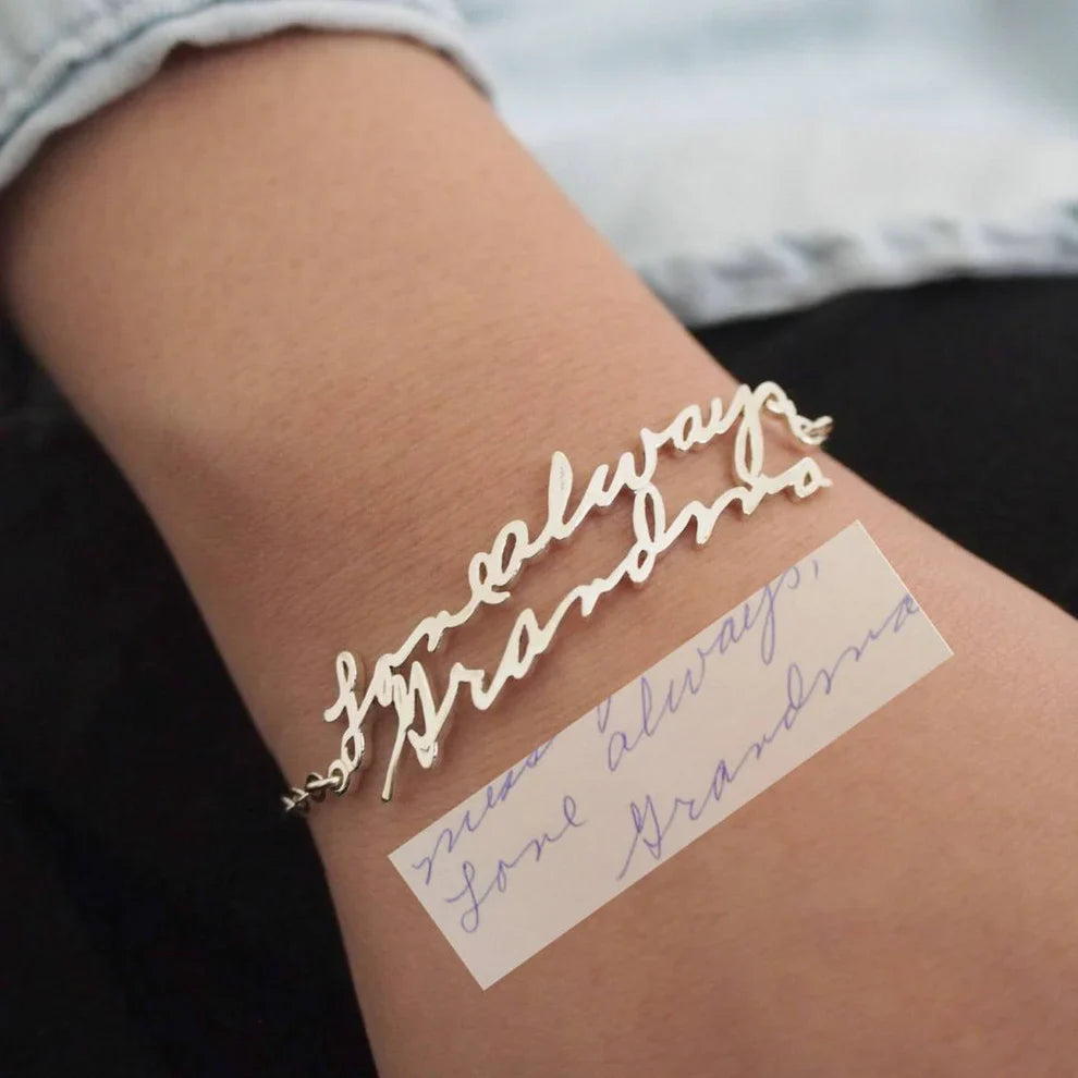 Gold bracelet with 'always' text on a wrist, matching a piece of paper with similar text.