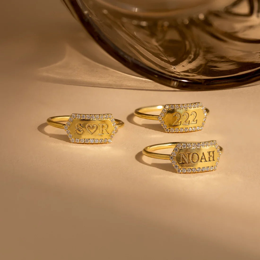 Three gold rings with engraved text on a beige surface